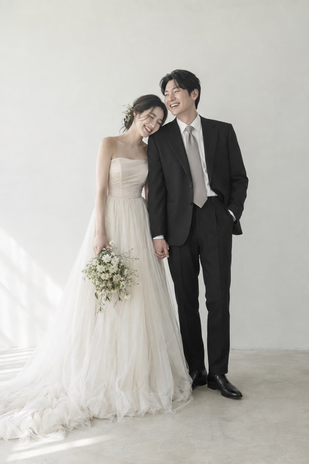 웨딩드레스와 정장을 입고 손을 잡은 채 웃고 있는 신랑 신부